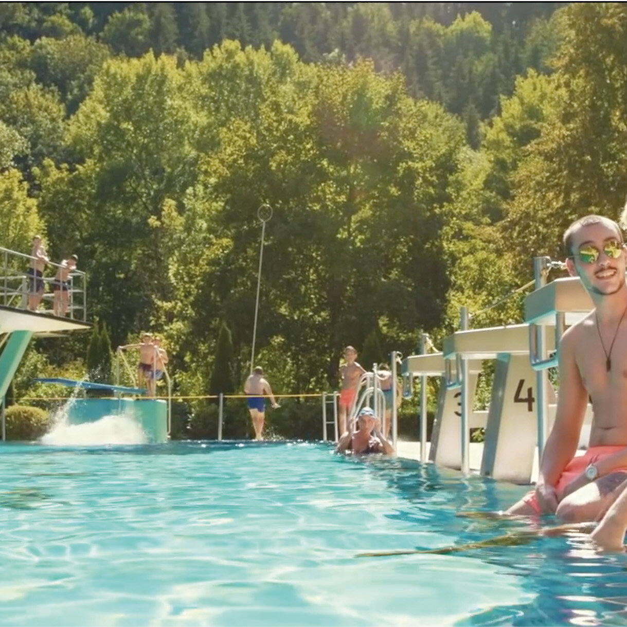 Zwei junge Männer am Beckenrand im Freibad