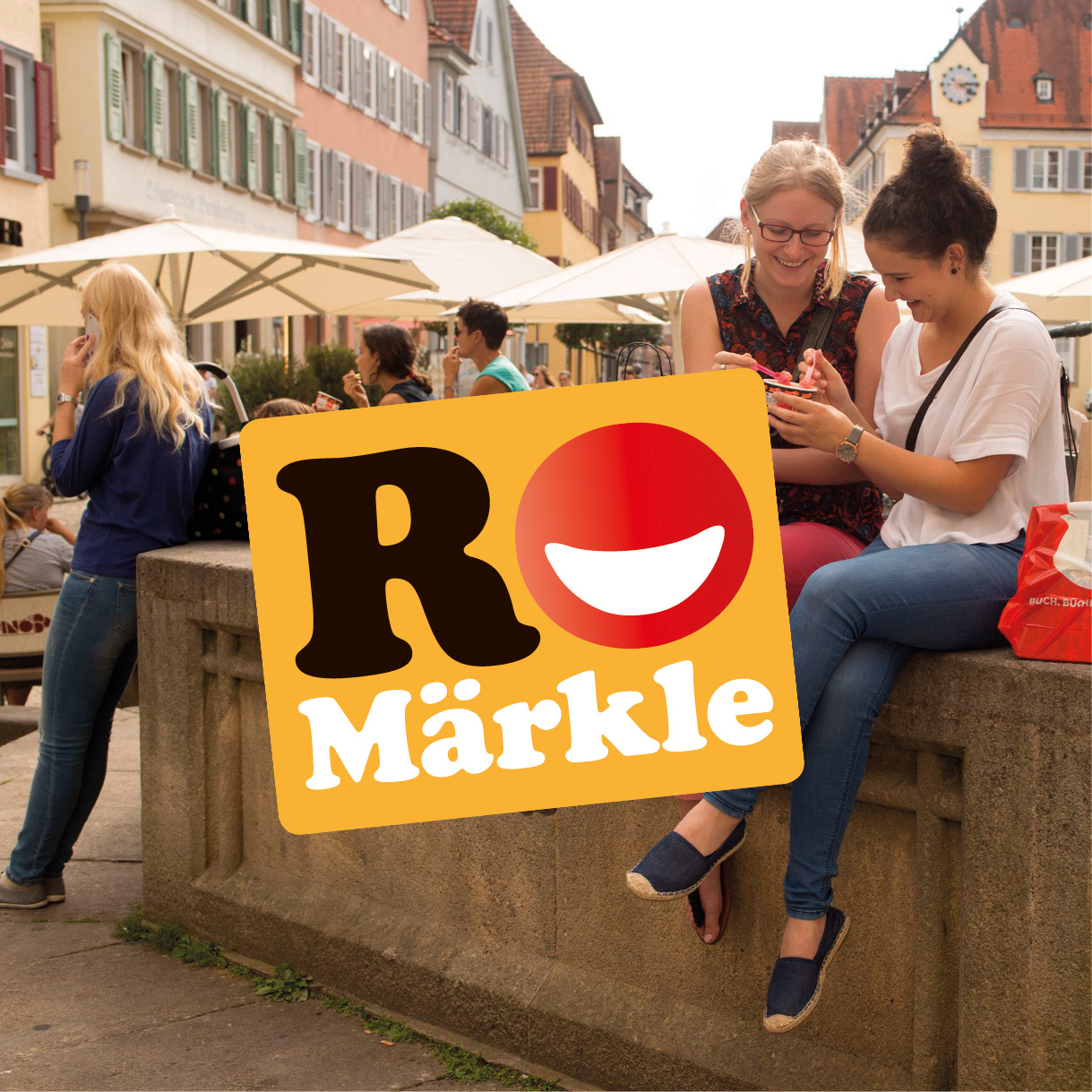 2 Mädchen sitzen auf dem Brunnen und essen Eis, davor das Logo RoMärkle
