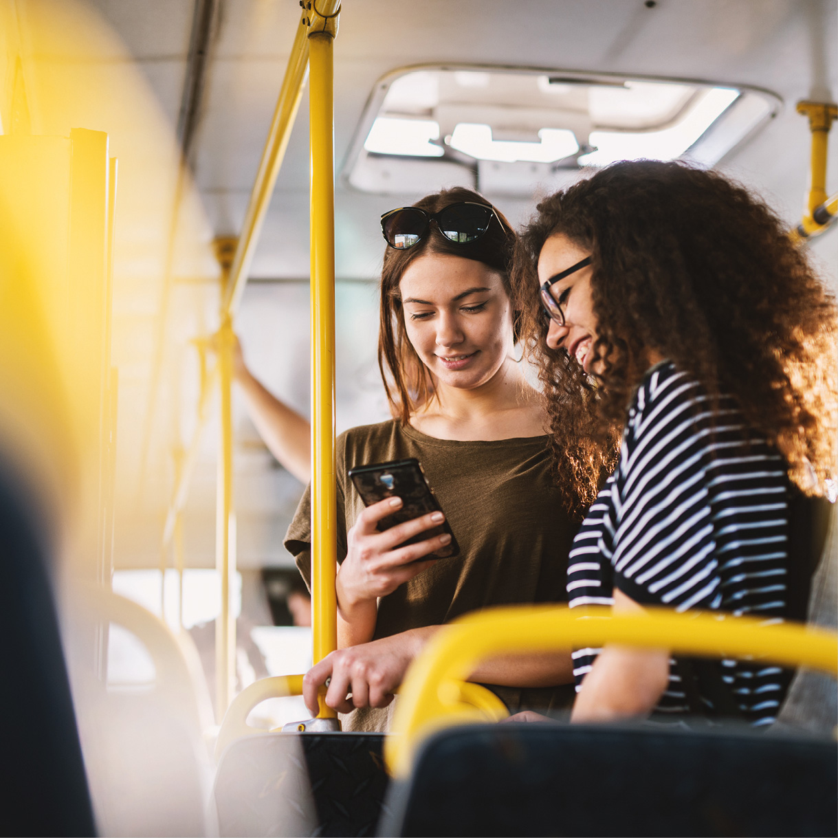 Zwei Frauen im Bus schauen auf Smartphone