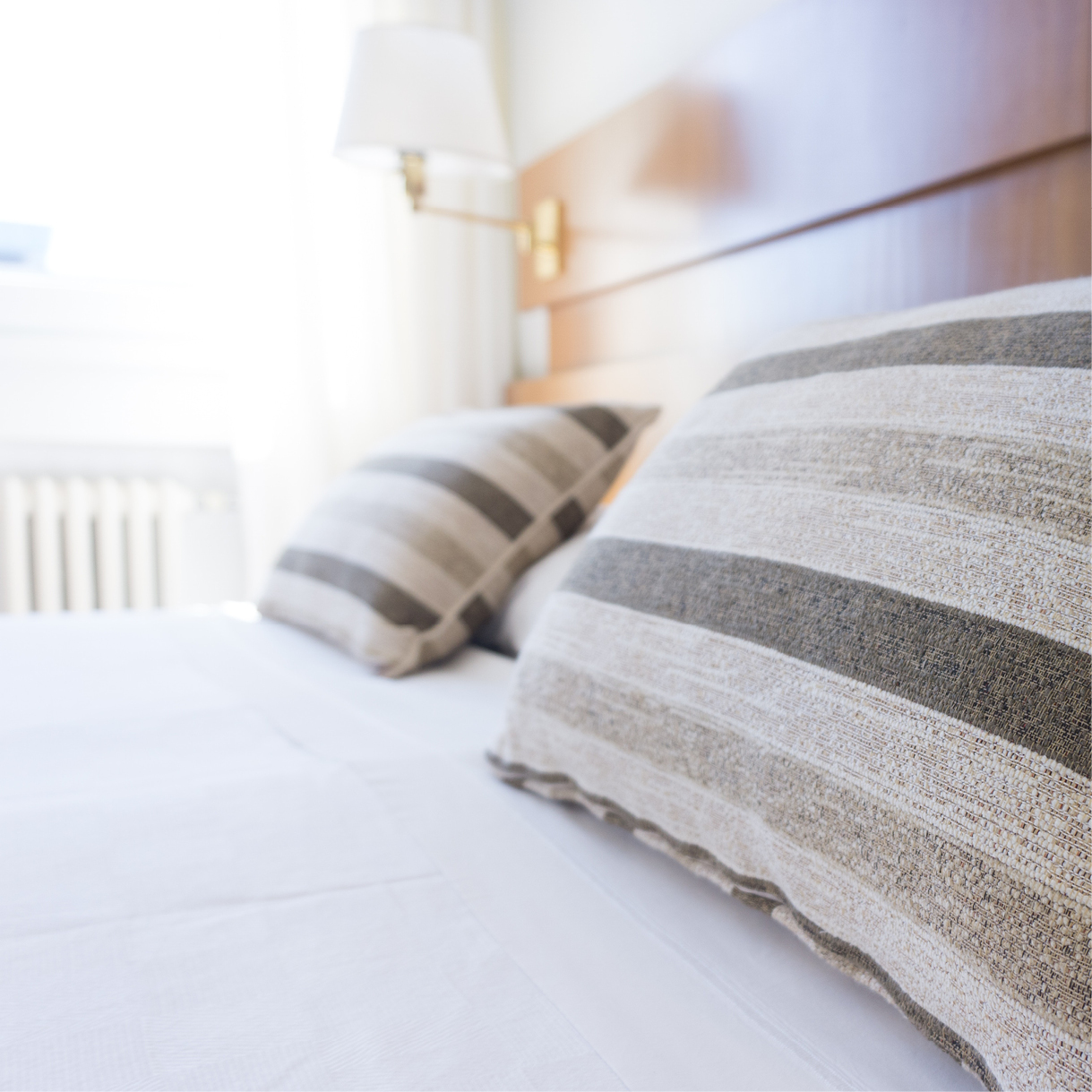 Ein Hotelbett mit gestreiften Kopfkissen. 