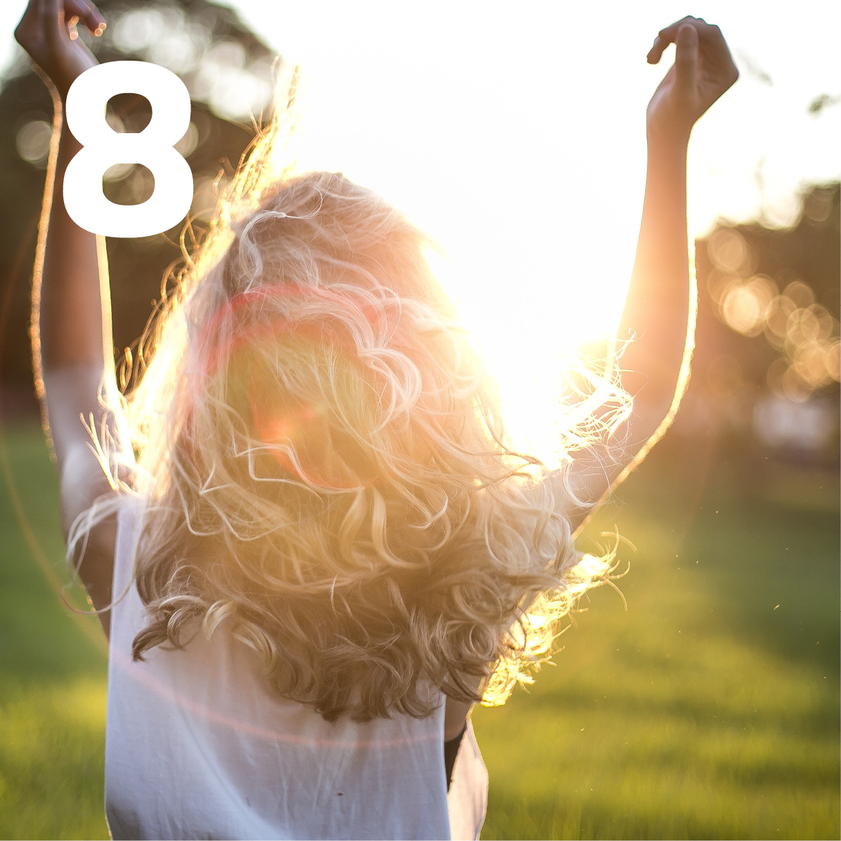 Mädchen hebt die Arme auf einer Wiese