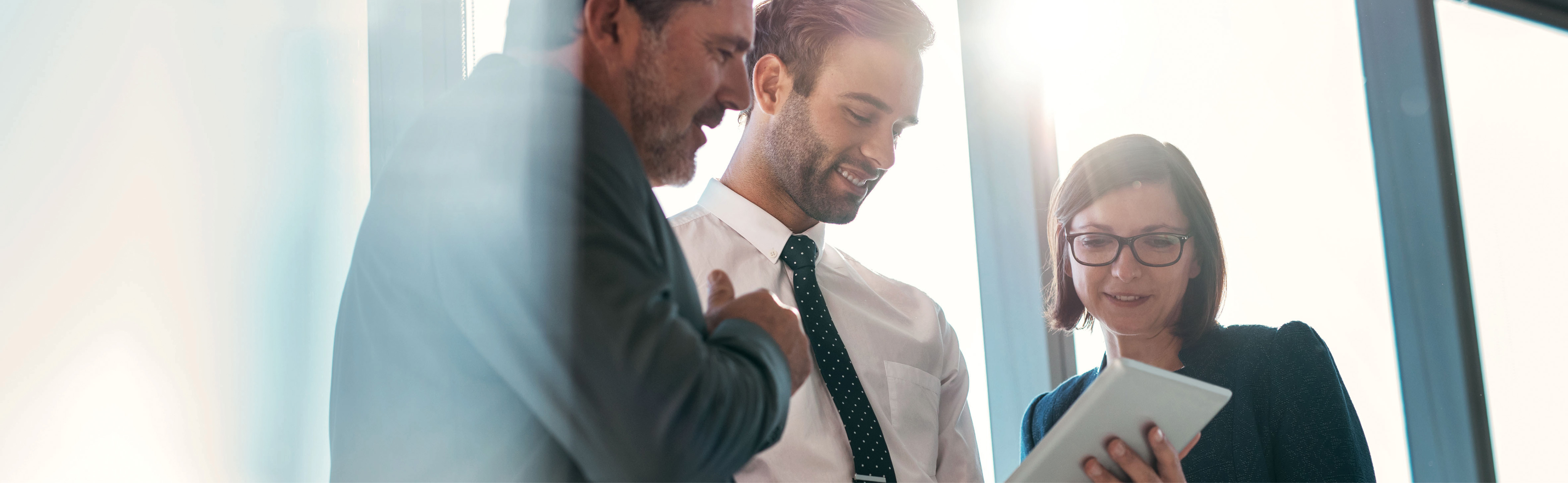 Drei Personen schauen auf ein Tablet